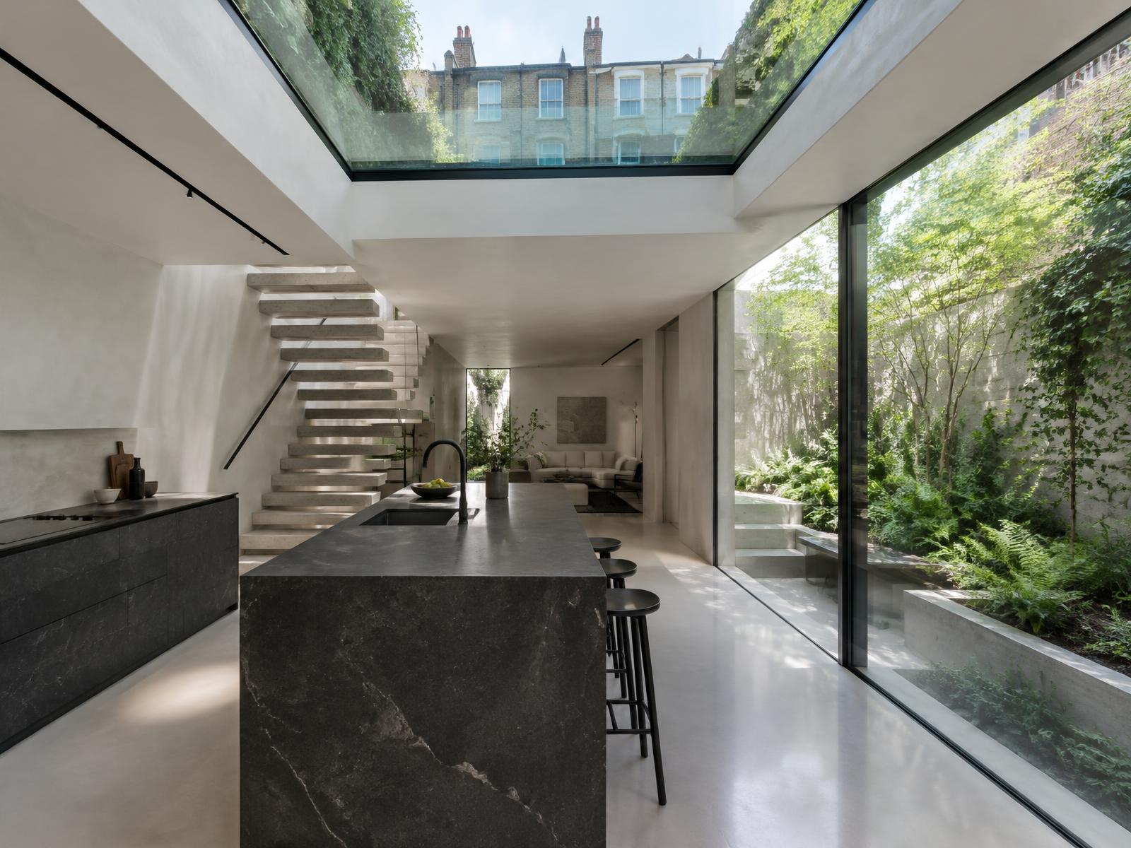 Basement kitchen with a floating stone stair, glass rooflight and glazing onto a sunken garden