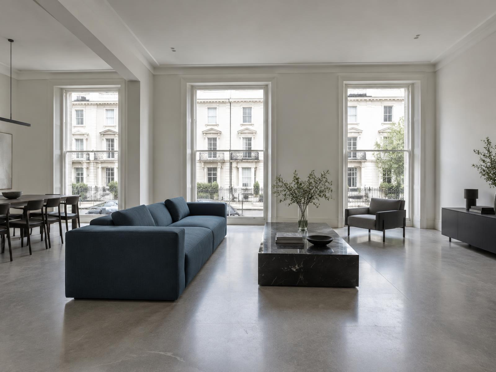 Minimalist room with a straight-lined petrol-blue sofa and tall windows onto stucco terraces