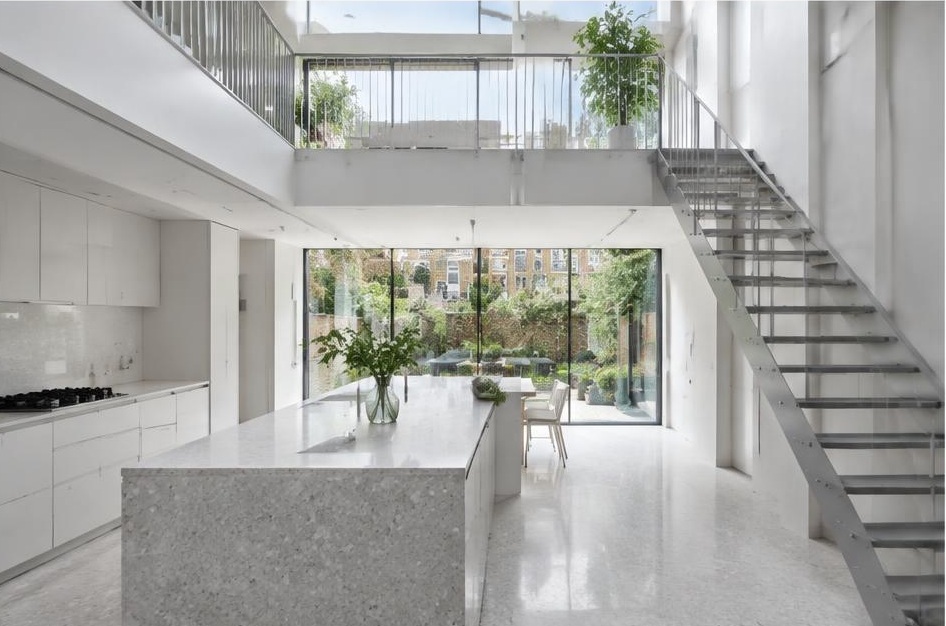 Contemporary kitchen with open staircase and glazing onto a residential garden in Balham