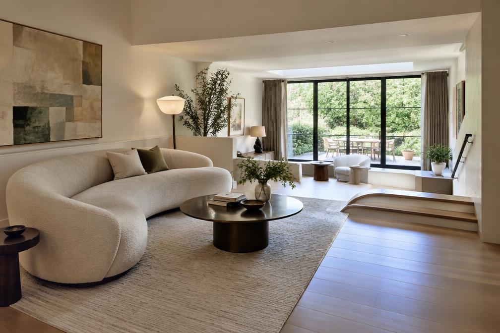 Living room with curved velvet sofa, tall sash windows and views over trees
