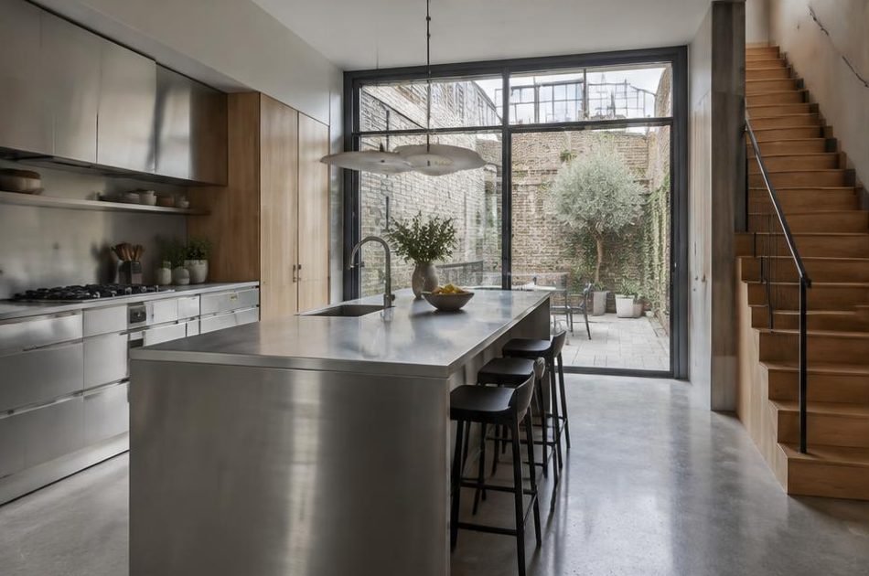 Contemporary kitchen with an open staircase and glazing onto a residential garden in Bermondsey