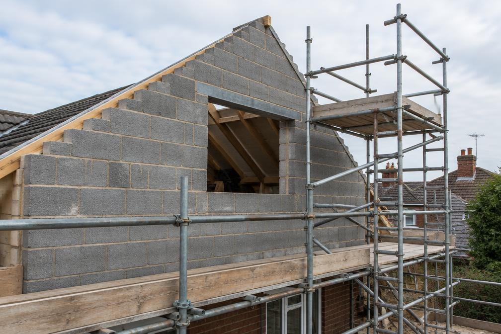 Bricklayer building a rear extension wall with a timber lintel frame