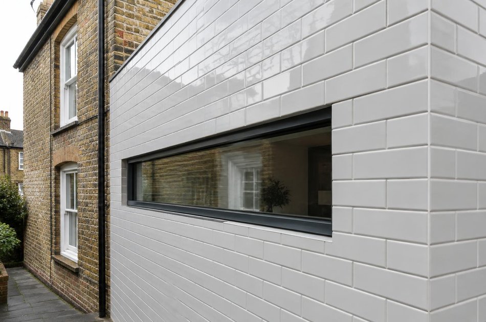 Victorian brick wall beside a glazed-brick side extension in Bowes Park