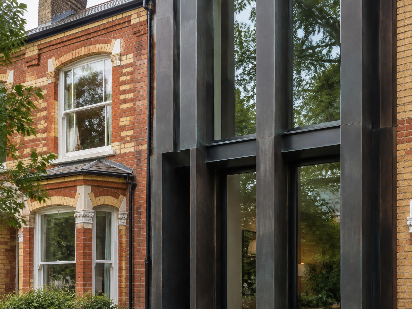 Victorian brick townhouse directly beside a contemporary infill with dark patinated metal fins and tall glazing
