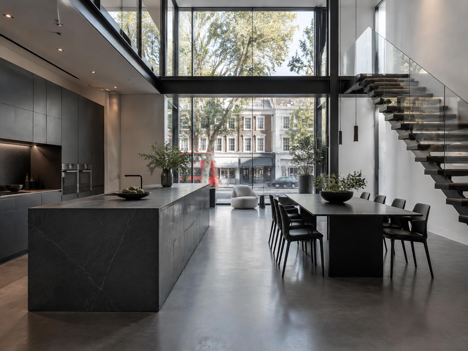Double-height contemporary kitchen with a basalt island and floating staircase, glazing framing a King's Road streetscape
