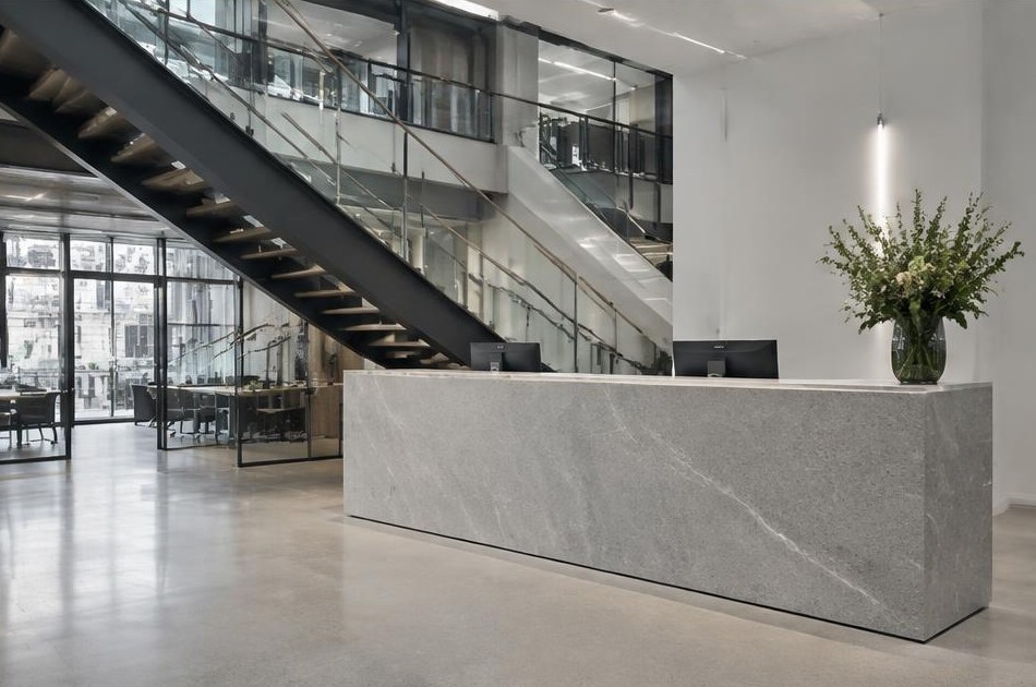 Completed contemporary office reception with stone desk and open staircase