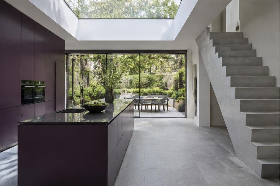 Contemporary kitchen with an open staircase and glazing onto a residential garden in Clapham