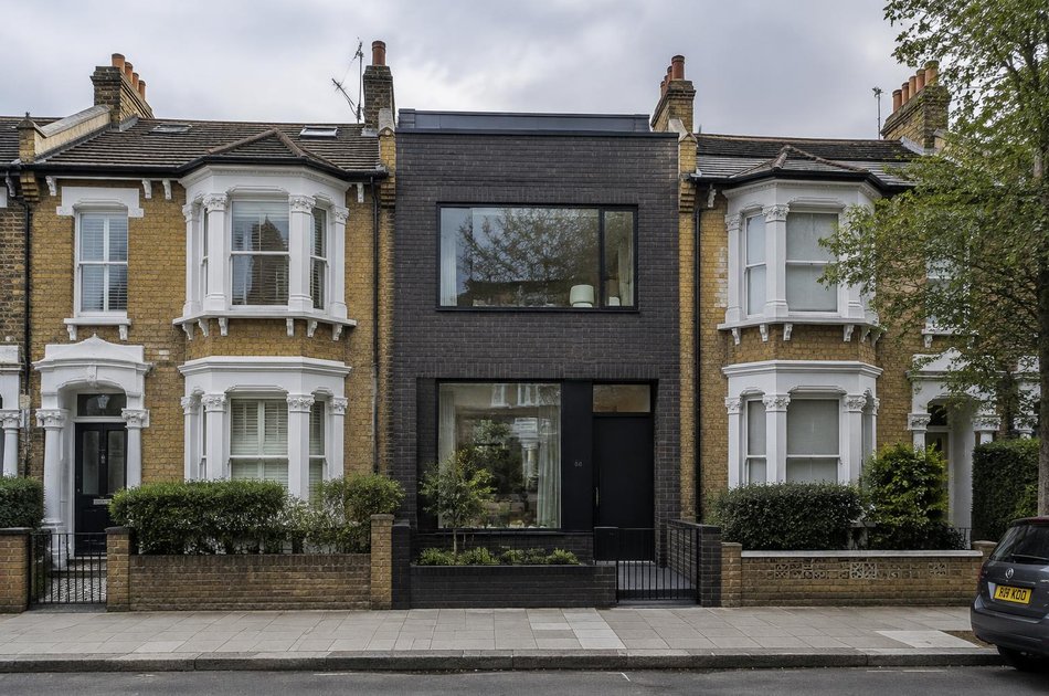 Victorian stock brick terraced street with a contemporary dark brick infill house in Colliers Wood