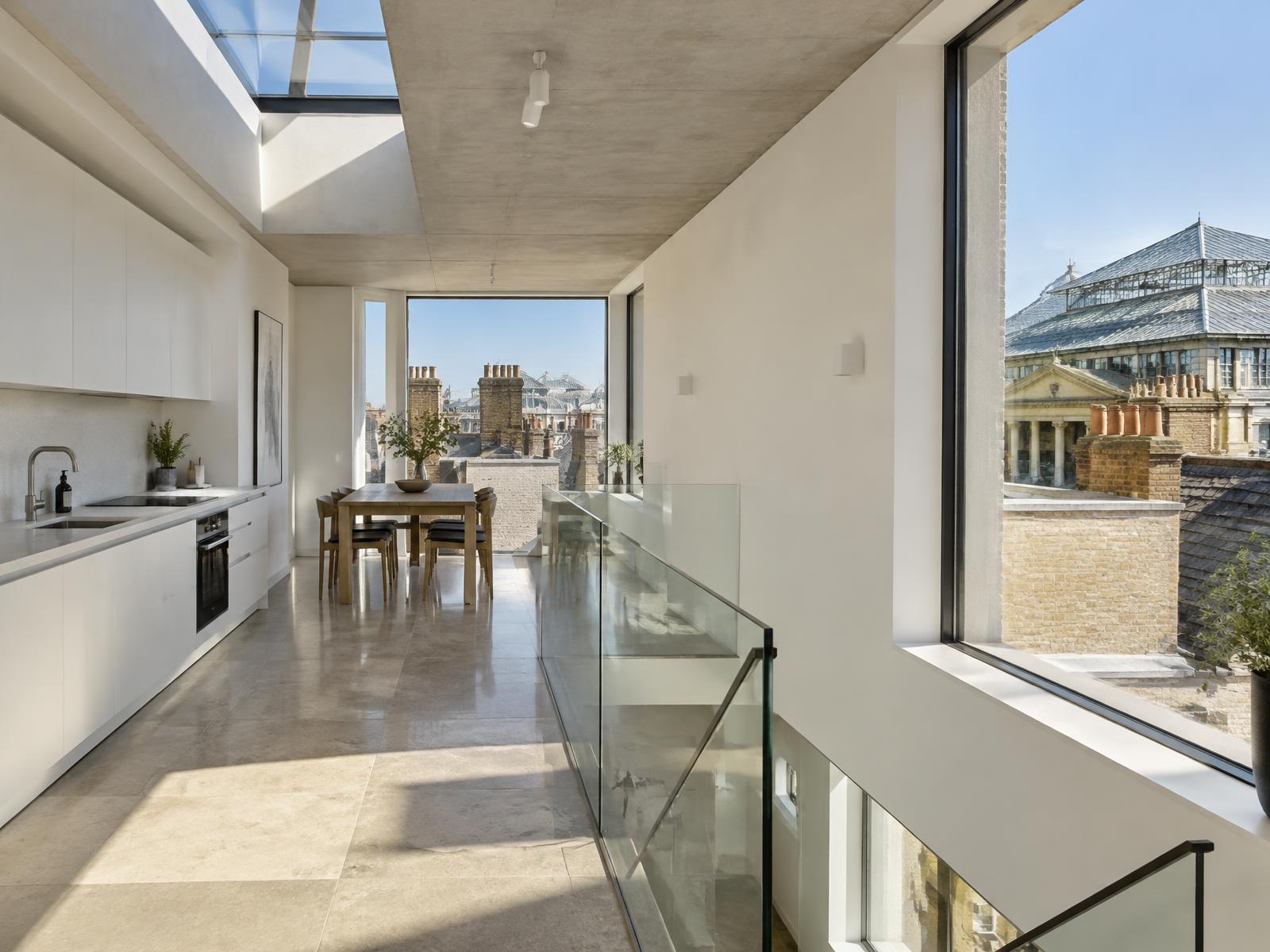 New top-floor space with a rooflight and glass stair looking across rooftops toward the Covent Garden market hall