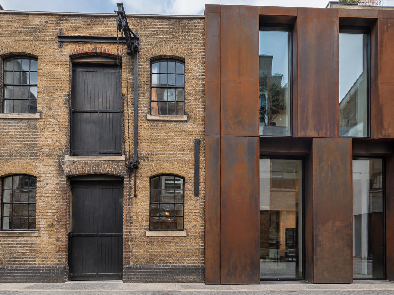 Victorian brick warehouse with loading doors directly beside a contemporary corten steel and glass building in Covent Garden