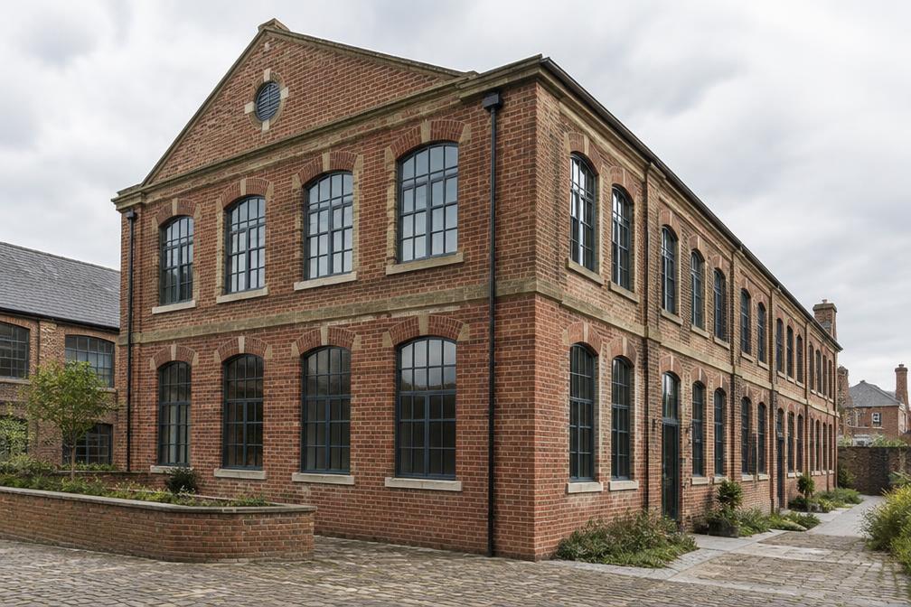 Restored brick industrial warehouse with new large windows by a small river
