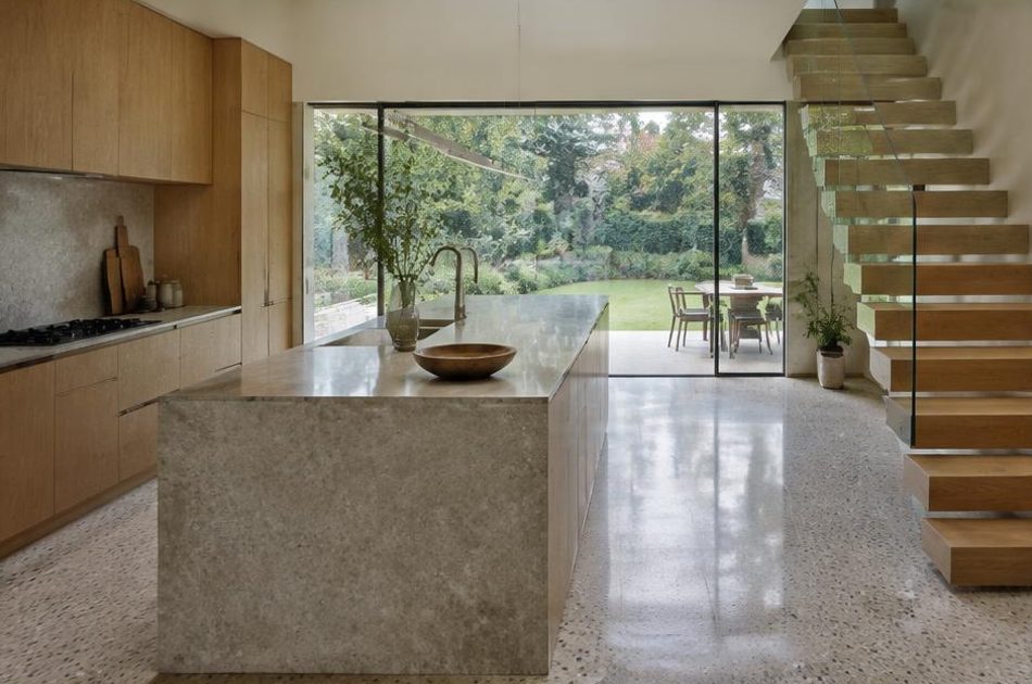 Contemporary kitchen with an open staircase and glazing onto a residential garden in Dulwich