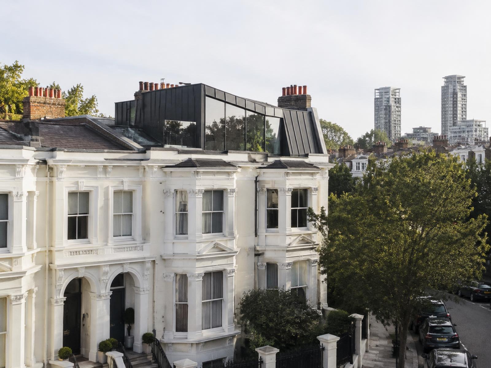 Victorian stucco terrace house with a dark zinc and glass roof extension