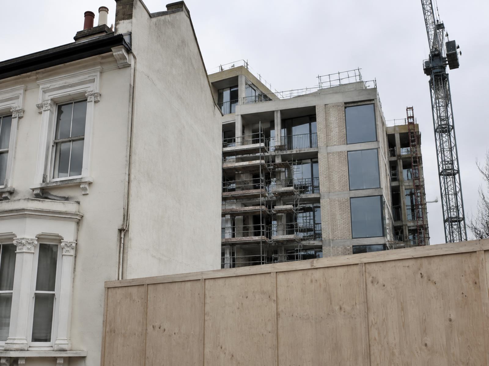 Stucco Victorian terrace directly beside hoarding and a new building under construction