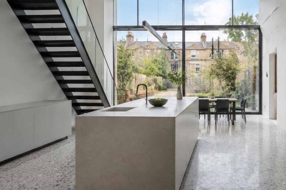 Contemporary kitchen with an open staircase and glazing onto a residential garden in Earlsfield