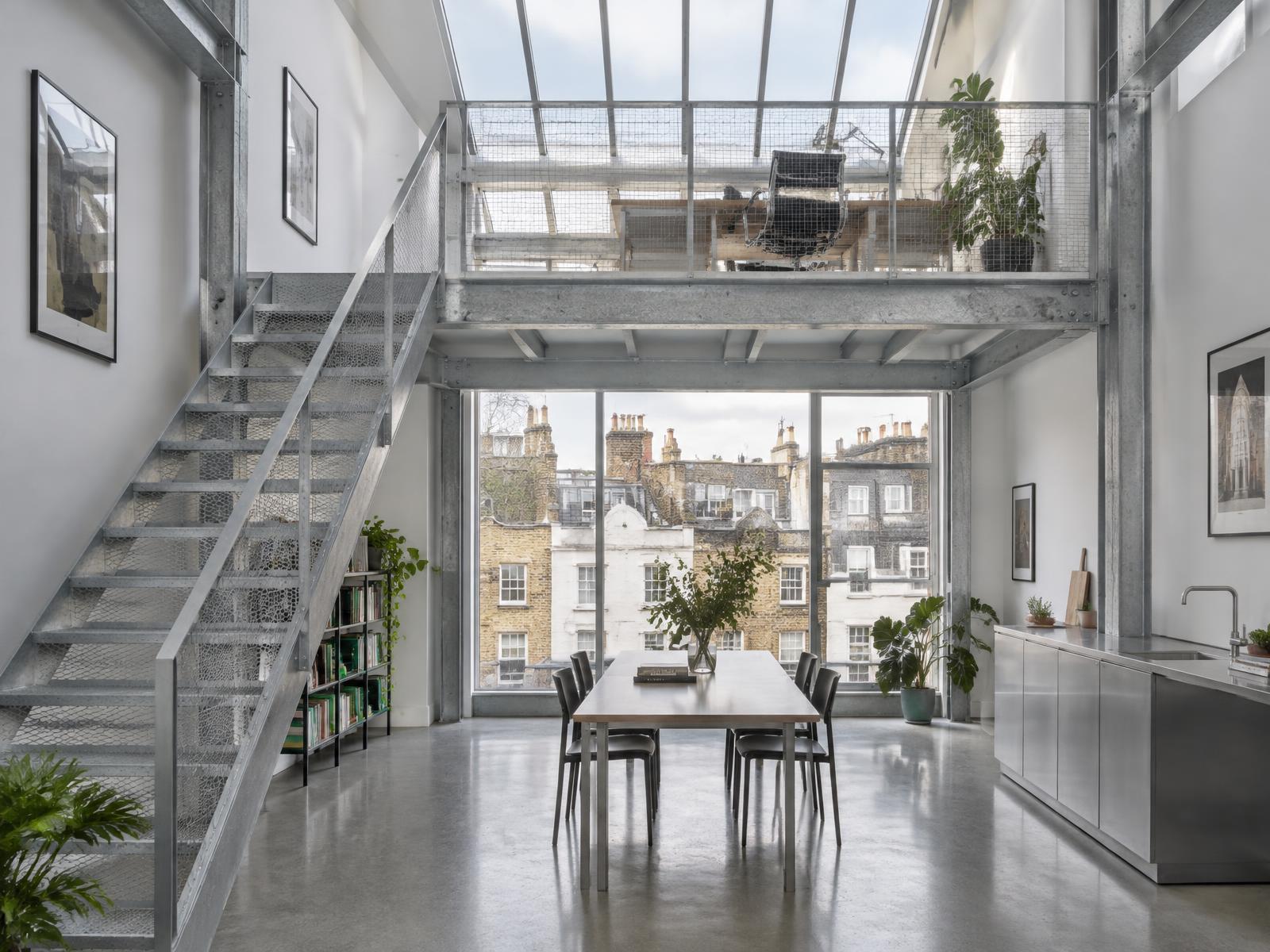 New double-height studio with a galvanised steel mezzanine and stair, glazed toward Fitzrovia rooftops
