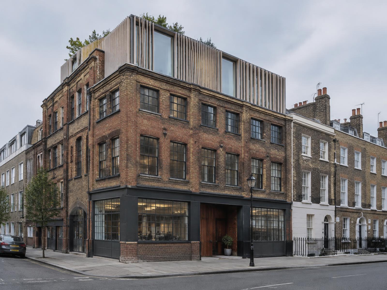 Victorian brick warehouse converted to studios with a contemporary timber-finned rooftop addition beside a Georgian terrace in Fitzrovia