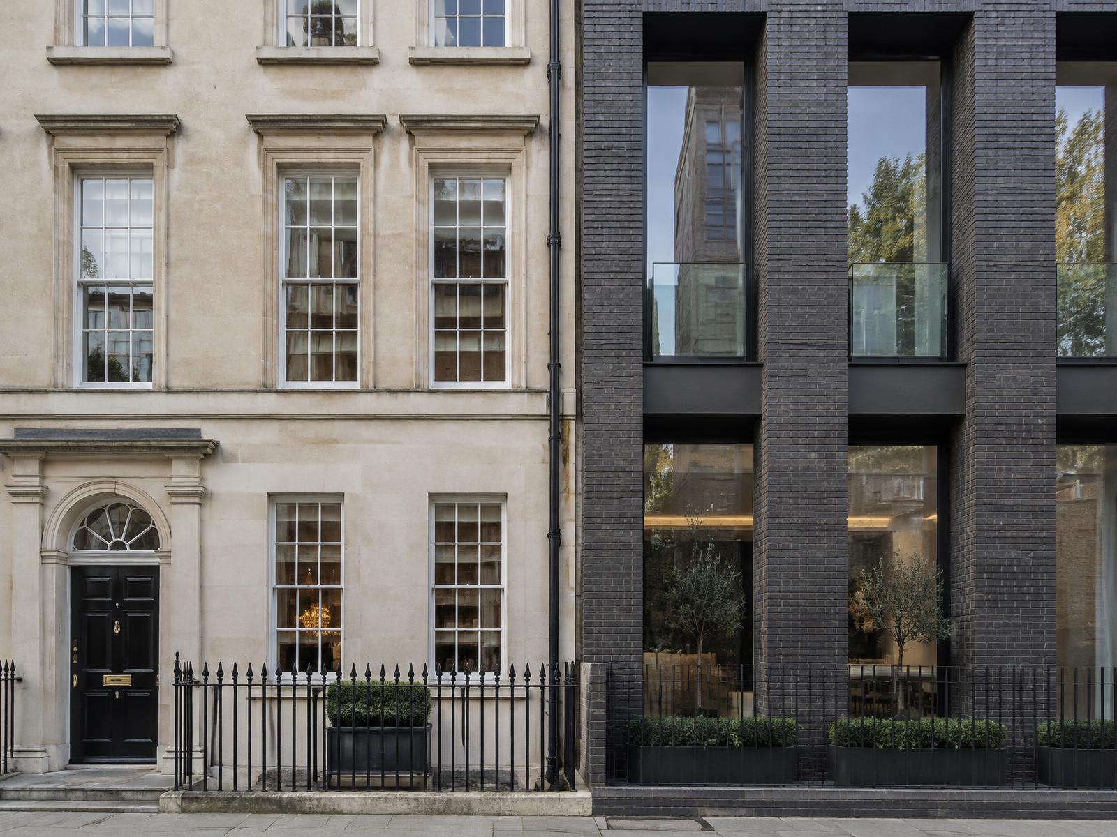 Georgian stone townhouse directly beside a contemporary dark brick and glass building in Fitzrovia