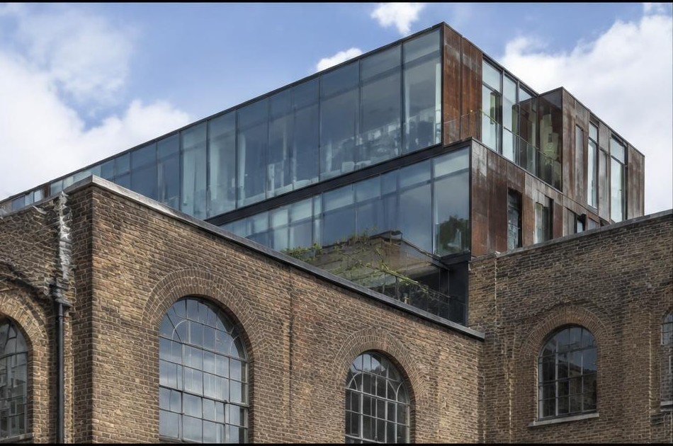 Retained original facade beside a dominant contemporary glazed addition in Hackney Wick