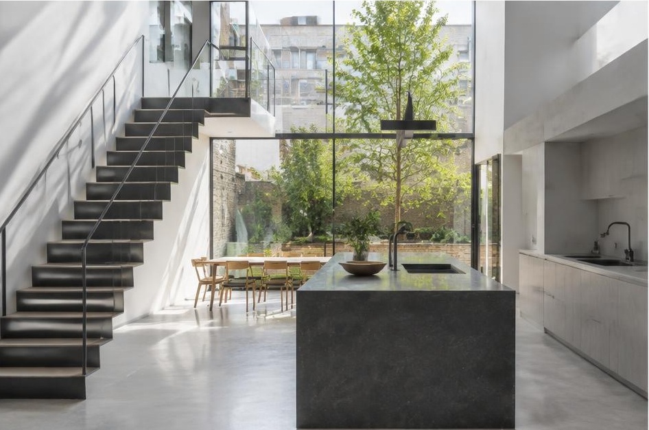 Contemporary kitchen with open staircase and glazing onto a residential garden in Balham