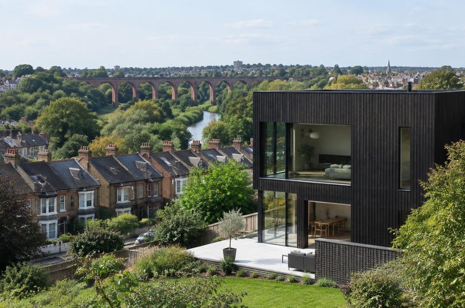 Brick railway viaduct across a green valley behind Victorian terraces and a contemporary timber house in Hanwell