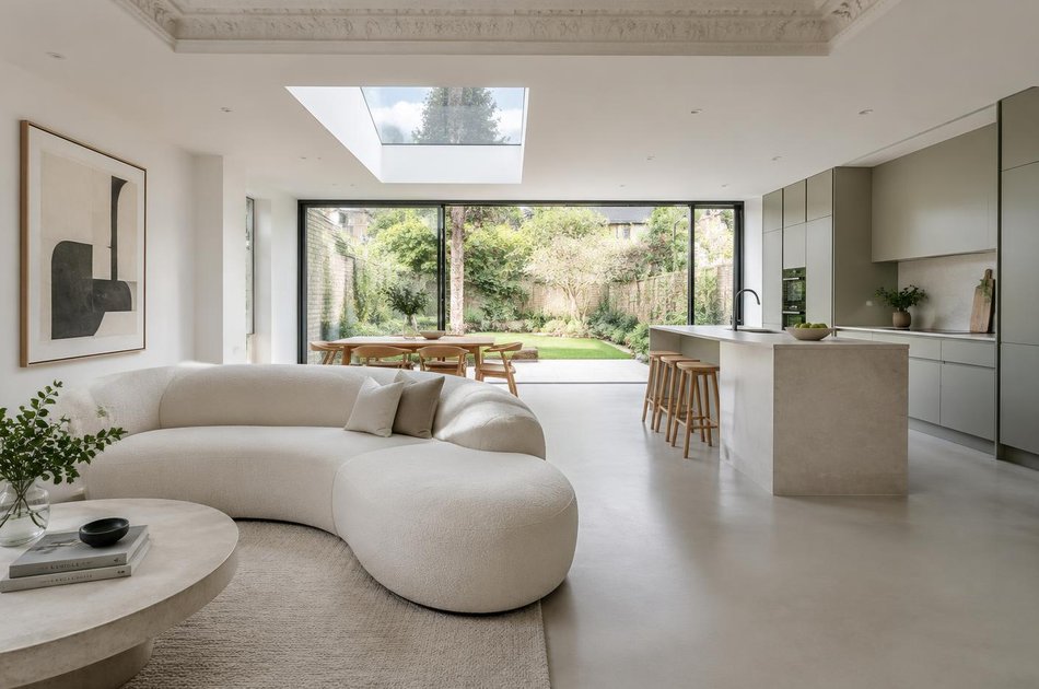 Refurbished open-plan interior with a curved sofa and retained cornice in Haringey