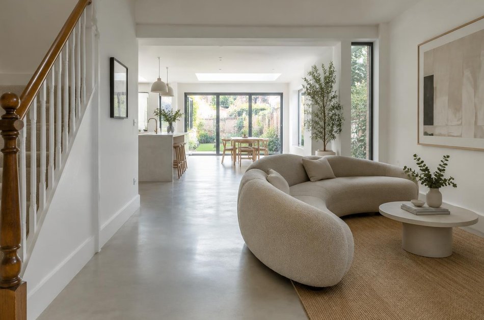 Refurbished interior with a curved sofa and retained handrail in Harringay