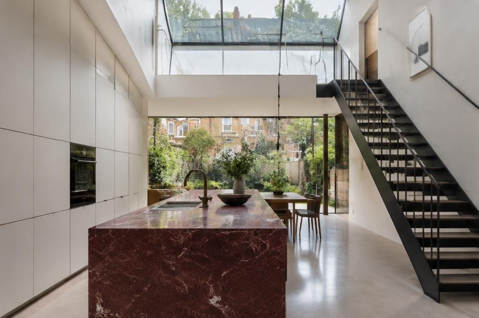 Contemporary kitchen with an open staircase and glazing onto a residential garden in Herne Hill