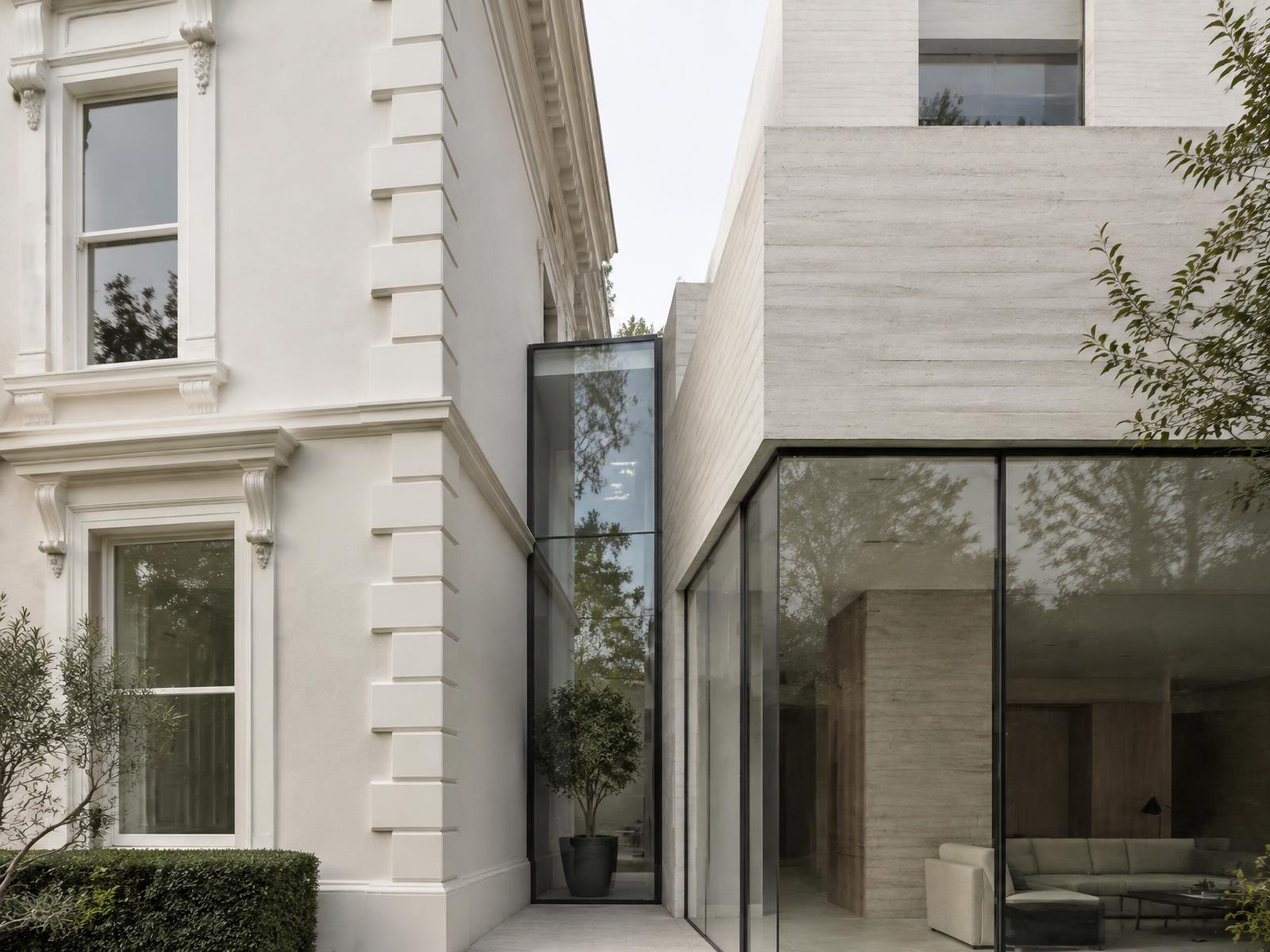 White stucco villa corner directly beside a board-marked concrete and glass villa wing