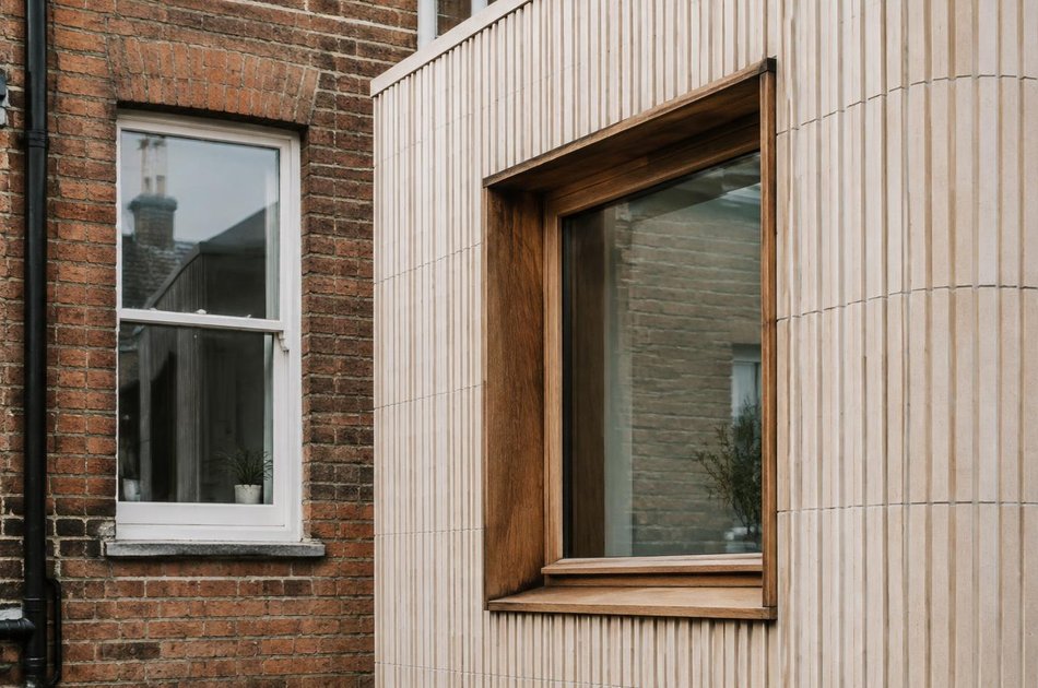 Victorian brick wall beside a terracotta-clad extension in Hornsey