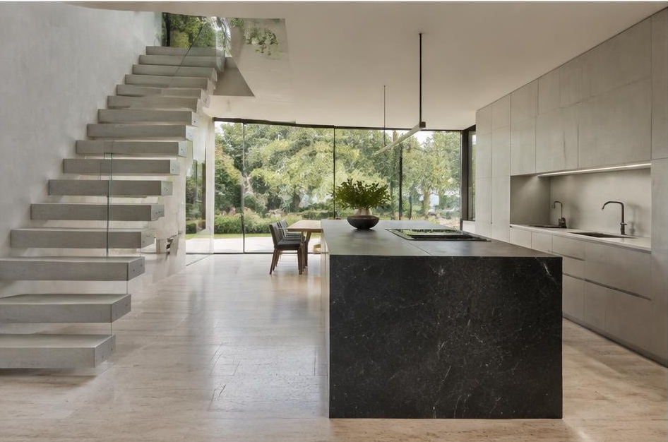 Contemporary kitchen with open staircase and glazing onto a residential garden in Hurlingham