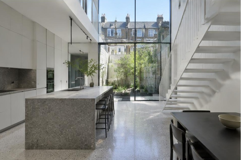 Contemporary kitchen with an open staircase and glazing onto a residential garden in Lambeth