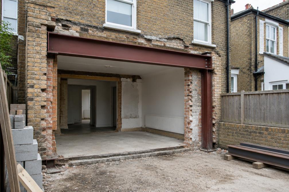 Steel beam being lifted into a terraced house rear wall during an extension build