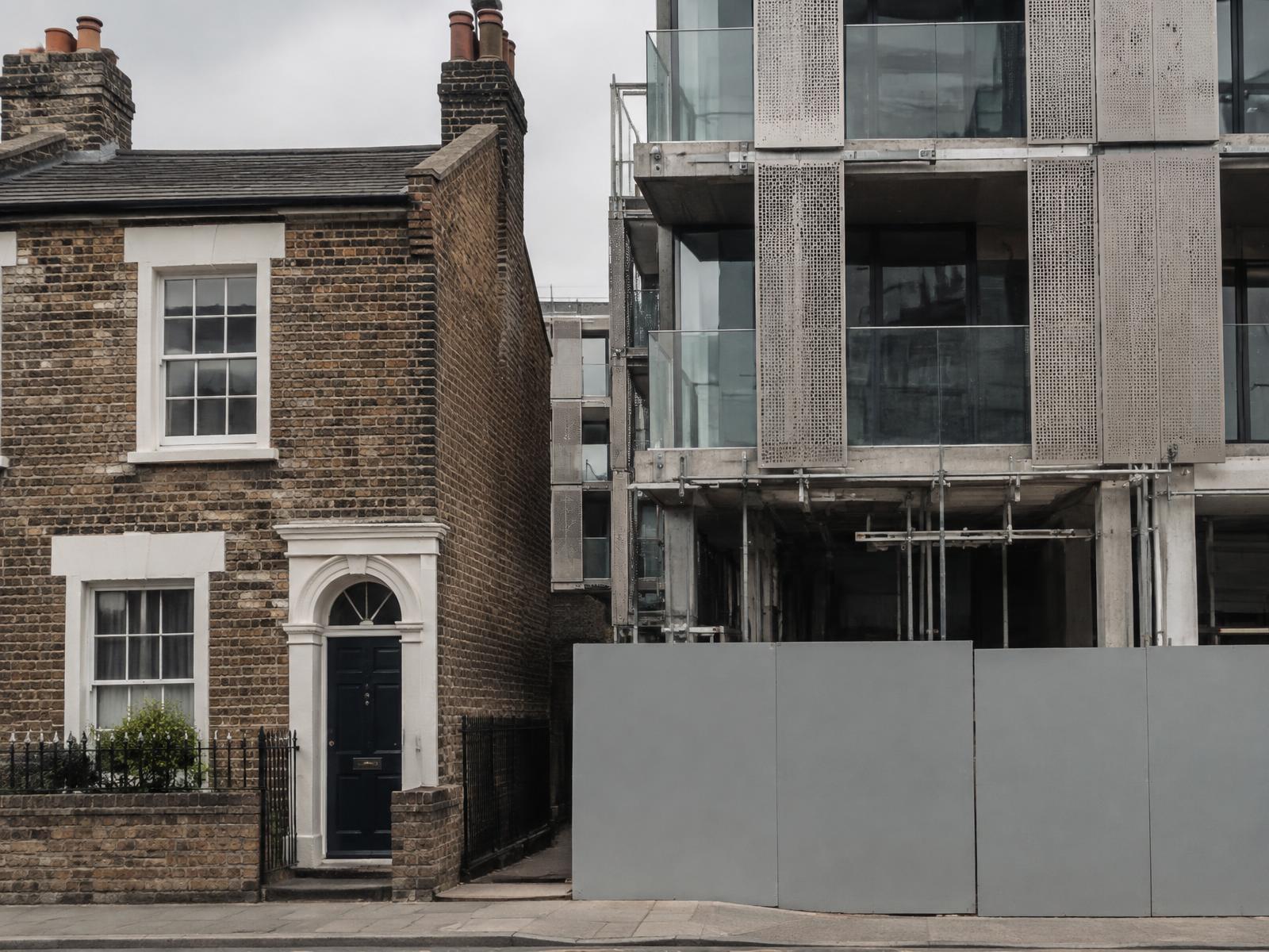 Stock brick Victorian cottage directly beside a new perforated metal and glass building under construction