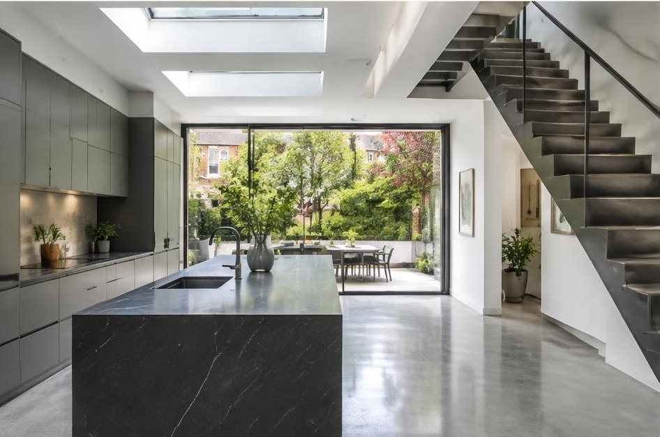 Contemporary kitchen with open staircase and glazing onto a residential garden in Northcote Road