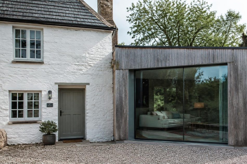 Whitewashed cottage beside a timber and glass extension in Northolt