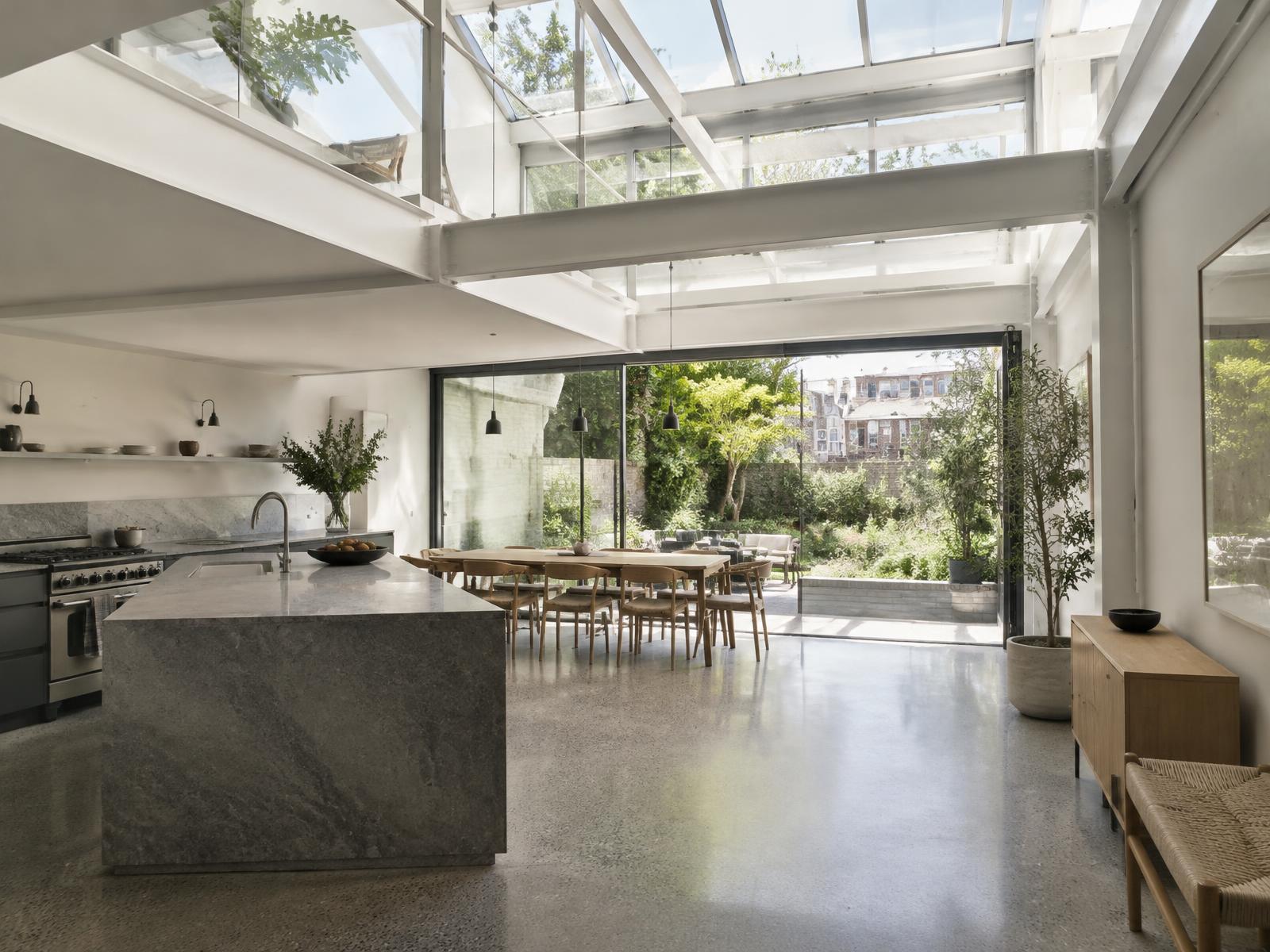 New double-height kitchen with a white steel frame and glazed roof opening onto a garden