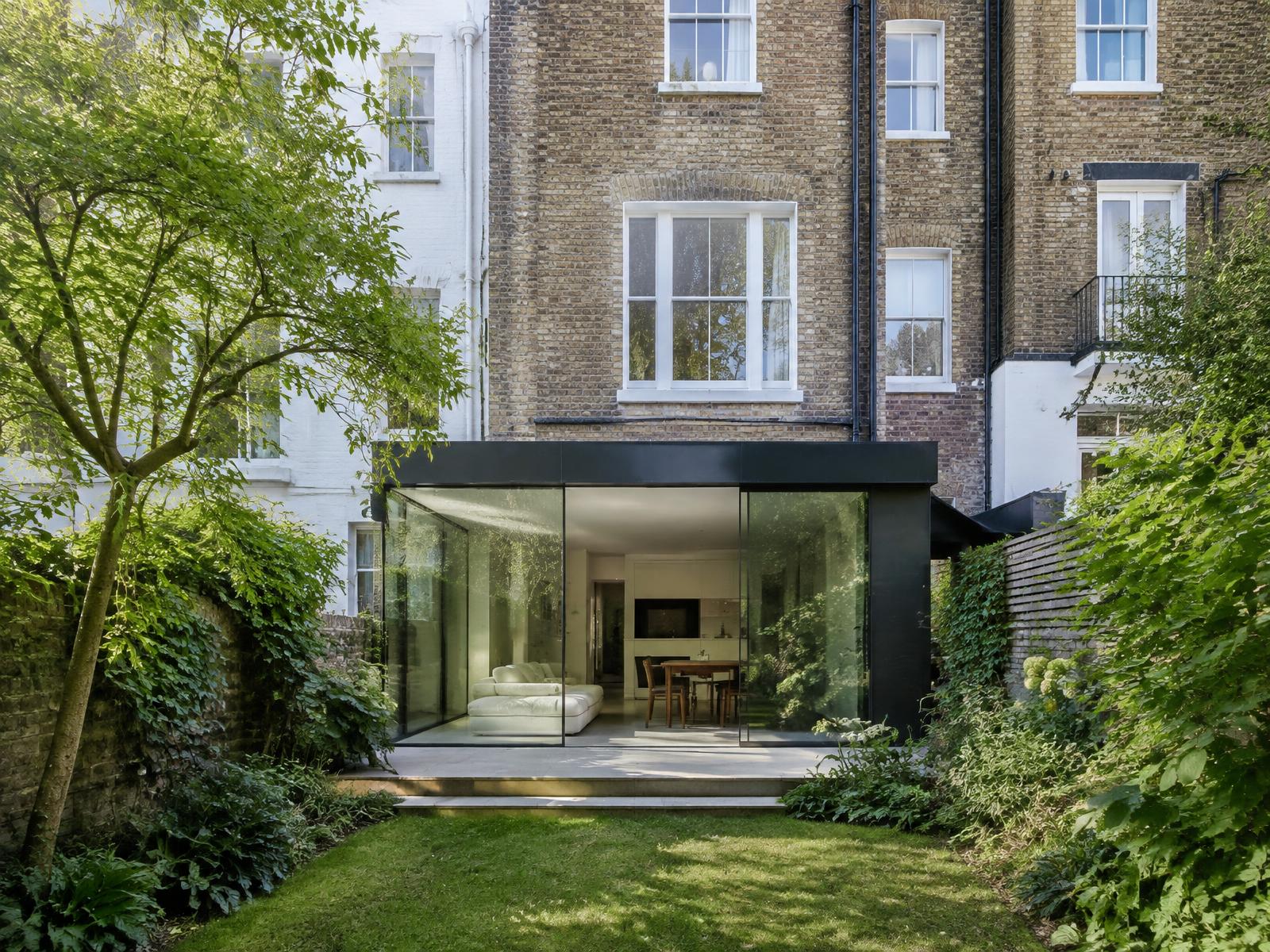 Stucco and brick terrace house with a black-framed glass rear extension onto a communal garden