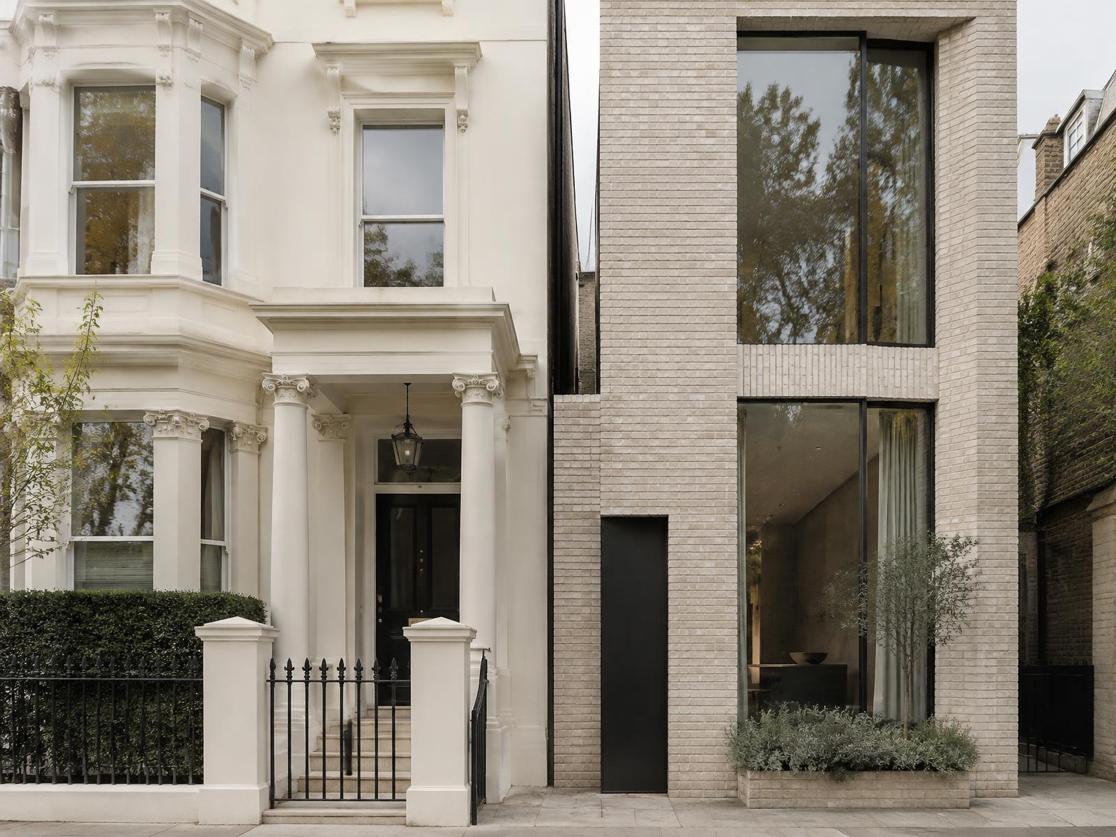 Cream stucco Victorian house with columned porch directly beside a contemporary pale brick house