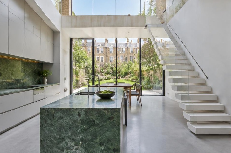 Contemporary kitchen with an open staircase and glazing onto a residential garden in Oval