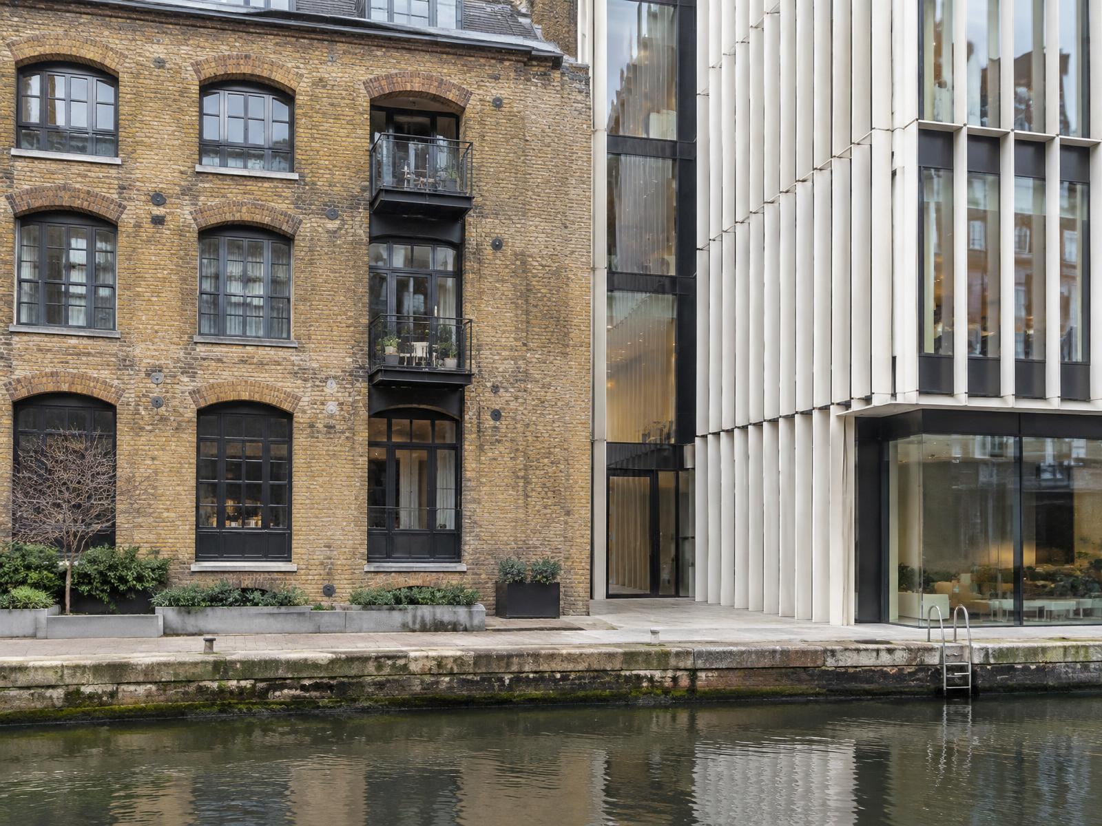 Converted brick canal warehouse directly beside a contemporary white-louvred glass building in Paddington