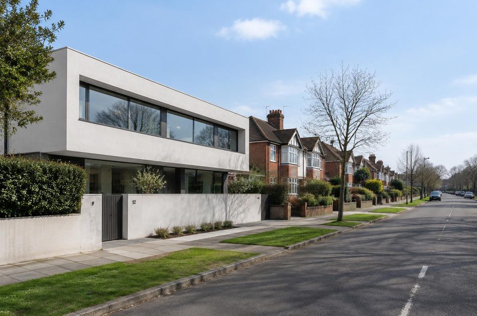 Interwar suburban road beside a contemporary white concrete house in Perivale