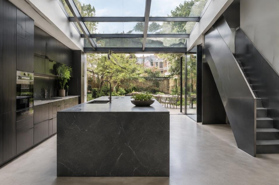 Contemporary kitchen with open staircase and glazing onto a residential garden in Putney