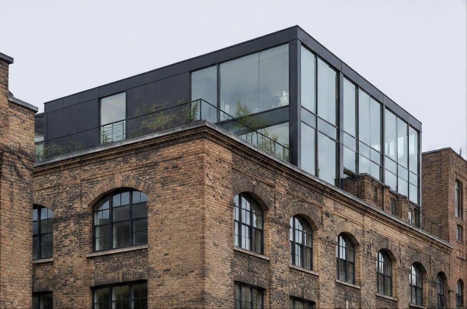Retained original facade beside a dominant contemporary glazed addition in Shoreditch