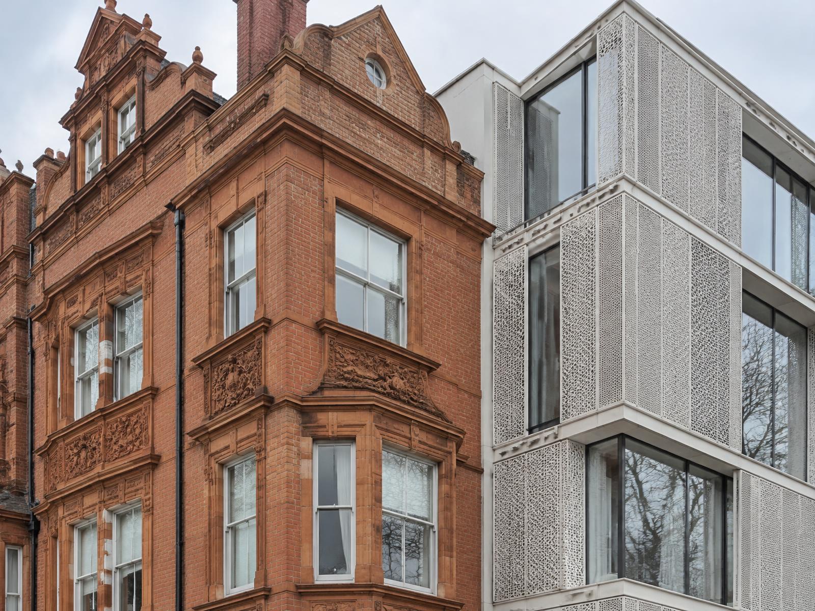Red-brick and terracotta South Kensington mansion block directly beside a contemporary building with perforated white screens