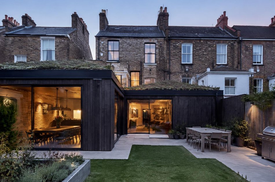 Dark timber wraparound extension with a green roof behind Edwardian terraces in South Wimbledon