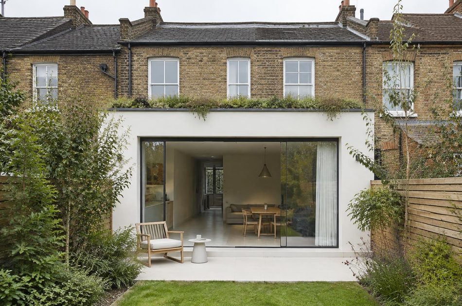 Rendered rear extension with a planted roof behind terraces in Southall
