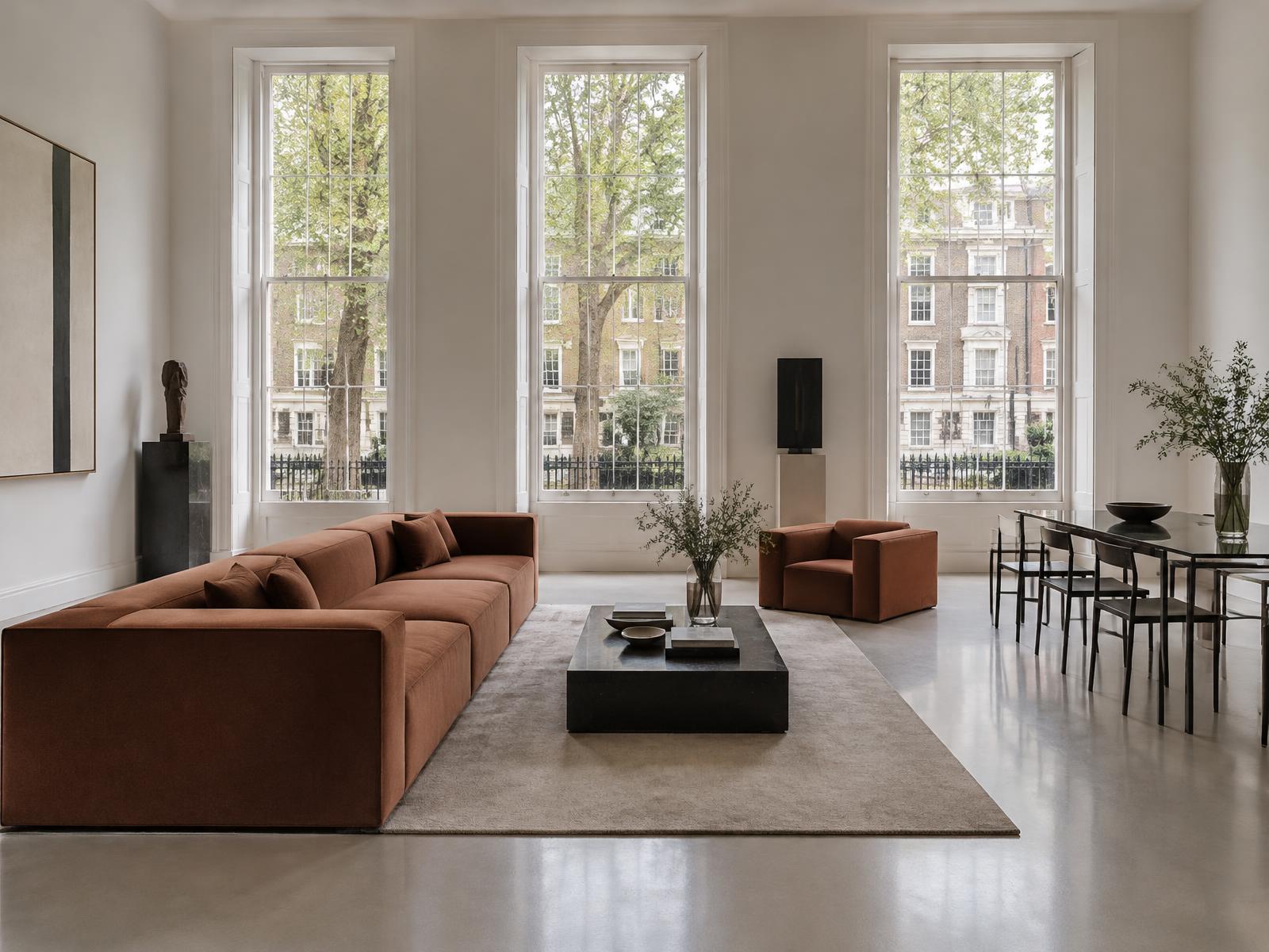 Minimalist tall-windowed room with a square-edged rust sofa overlooking St James's Square
