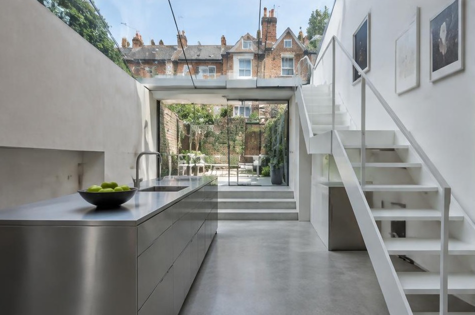 Contemporary kitchen with an open staircase and glazing onto a residential garden in Tooting