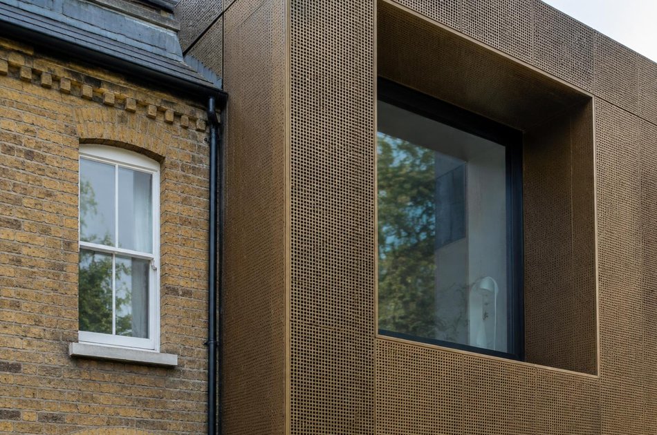 Victorian brick facade beside a bronze-clad extension in Tottenham